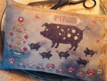 Decorative pillow featuring a polka dot pig, sheep, and floral design, in muted blue and earthy tones.