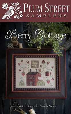 Framed embroidery design 'Berry Cottage' by Plum Street Samplers, featuring a charming red house and floral motifs.
