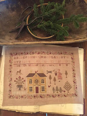 Hand-stitched embroidery sampler featuring a house, trees, and decorative elements on linen fabric.
