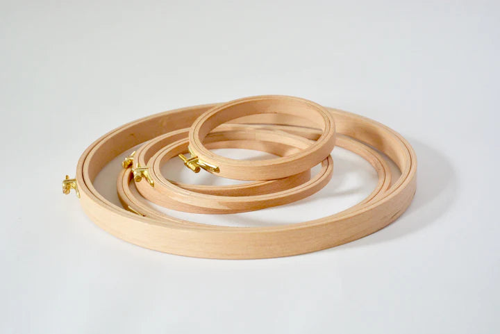 Set of wooden embroidery hoops in three sizes with gold clasps for secure fabric hold.