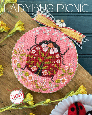 Circular fabric design featuring a colorful ladybug on a pink background with floral accents.