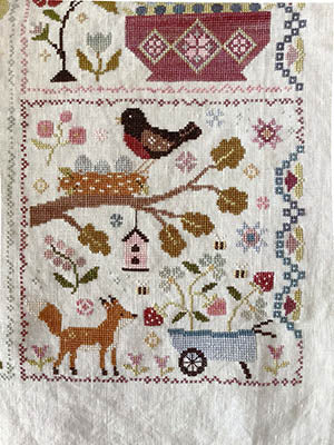 Hand-stitched embroidery featuring a bird, fox, and flowers on linen fabric, colorful nature-themed design.
