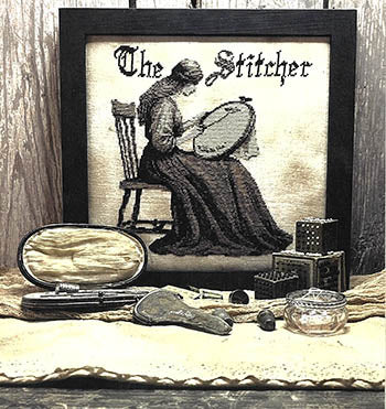 Framed cross stitch art titled 'The Stitcher', featuring a woman in a dark dress, vintage sewing tools.