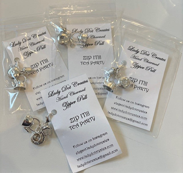 Handcrafted silver zipper pulls featuring tea-themed charms in unique packaging by Lady Dot Creates.