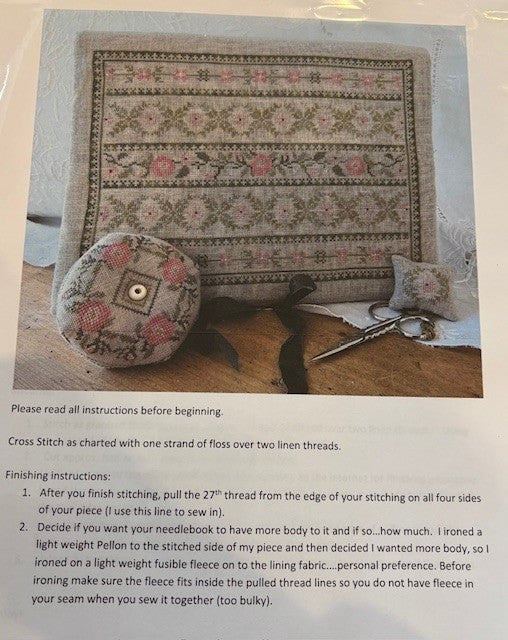 Cross stitch kit featuring floral design, including a needle book and pincushion in soft pastel colors.