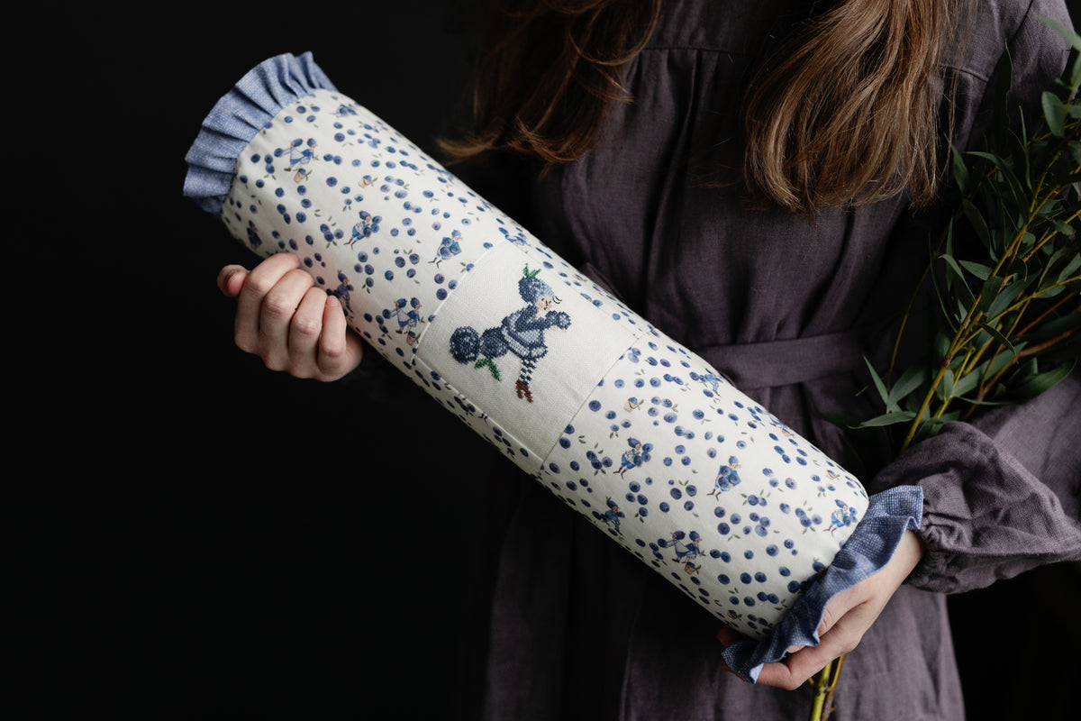 Decorative floral pillow, blue and cream fabric, featuring charming embroidery and ruffled edges.