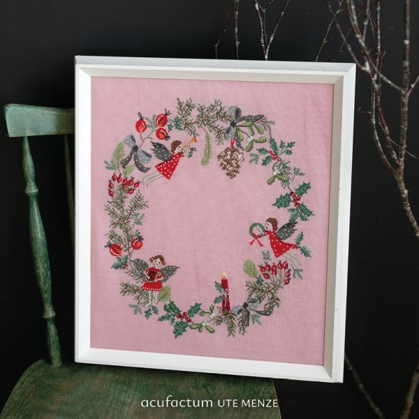 Framed festive embroidery of angels and greenery on pink fabric, perfect for holiday decor.