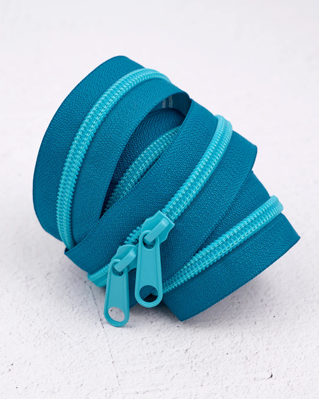 Roll of turquoise zippers, durable nylon material, ideal for sewing and crafting projects.