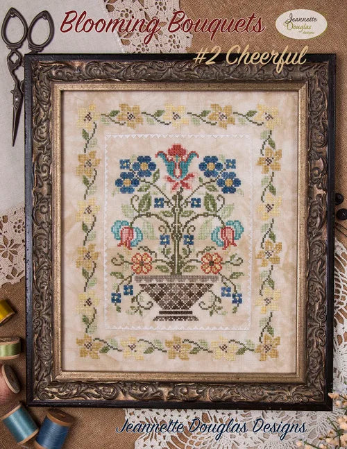 Framed cross-stitch art 'Blooming Bouquets #2 Cheerful' by Jeannette Douglas, featuring colorful flowers and vase.