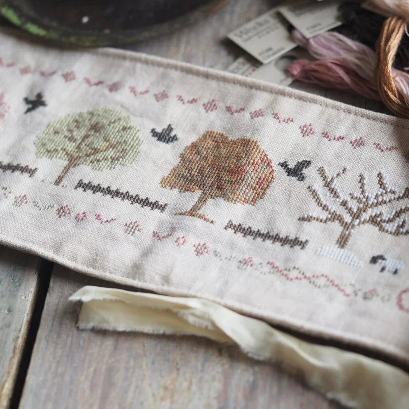 Embroidered linen tapestry featuring colorful trees and birds in soft hues, perfect for home decor.