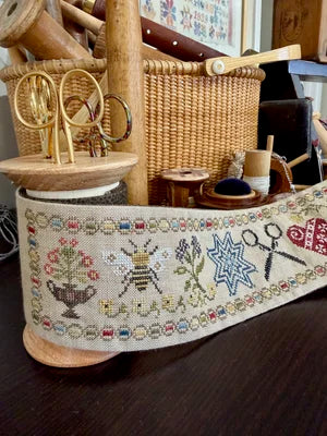 Decorative stitched band featuring bees, scissors, and floral designs on natural linen fabric.
