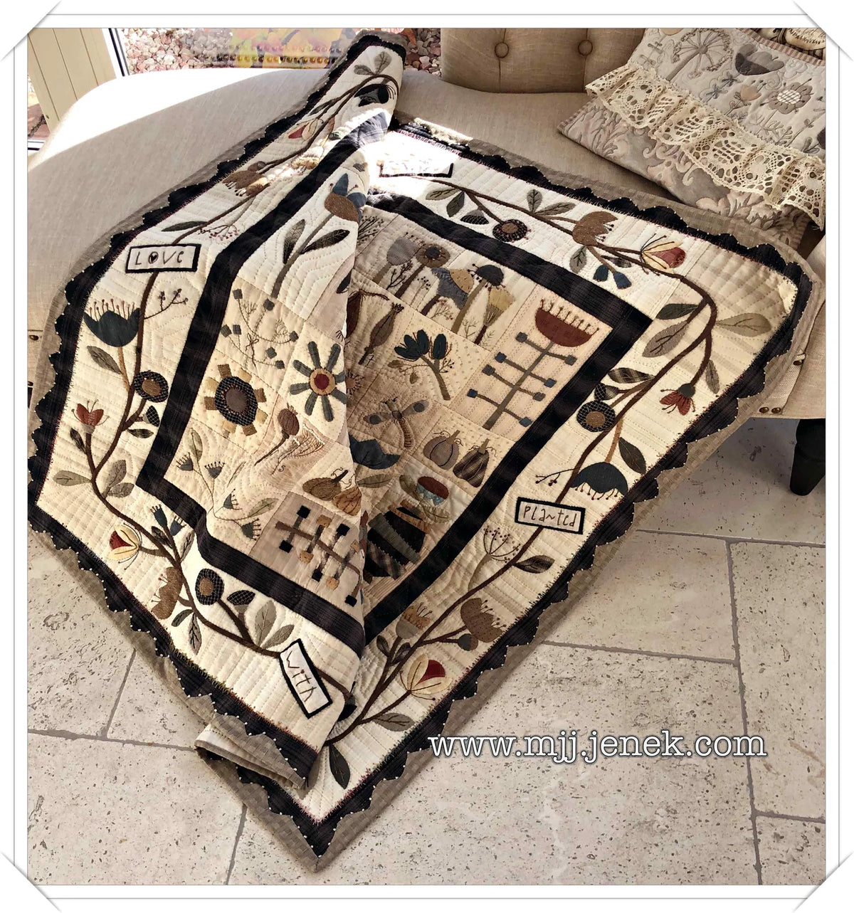 Quilted floral throw blanket in cream and black, featuring embroidered plants and birds, perfect for home decor.