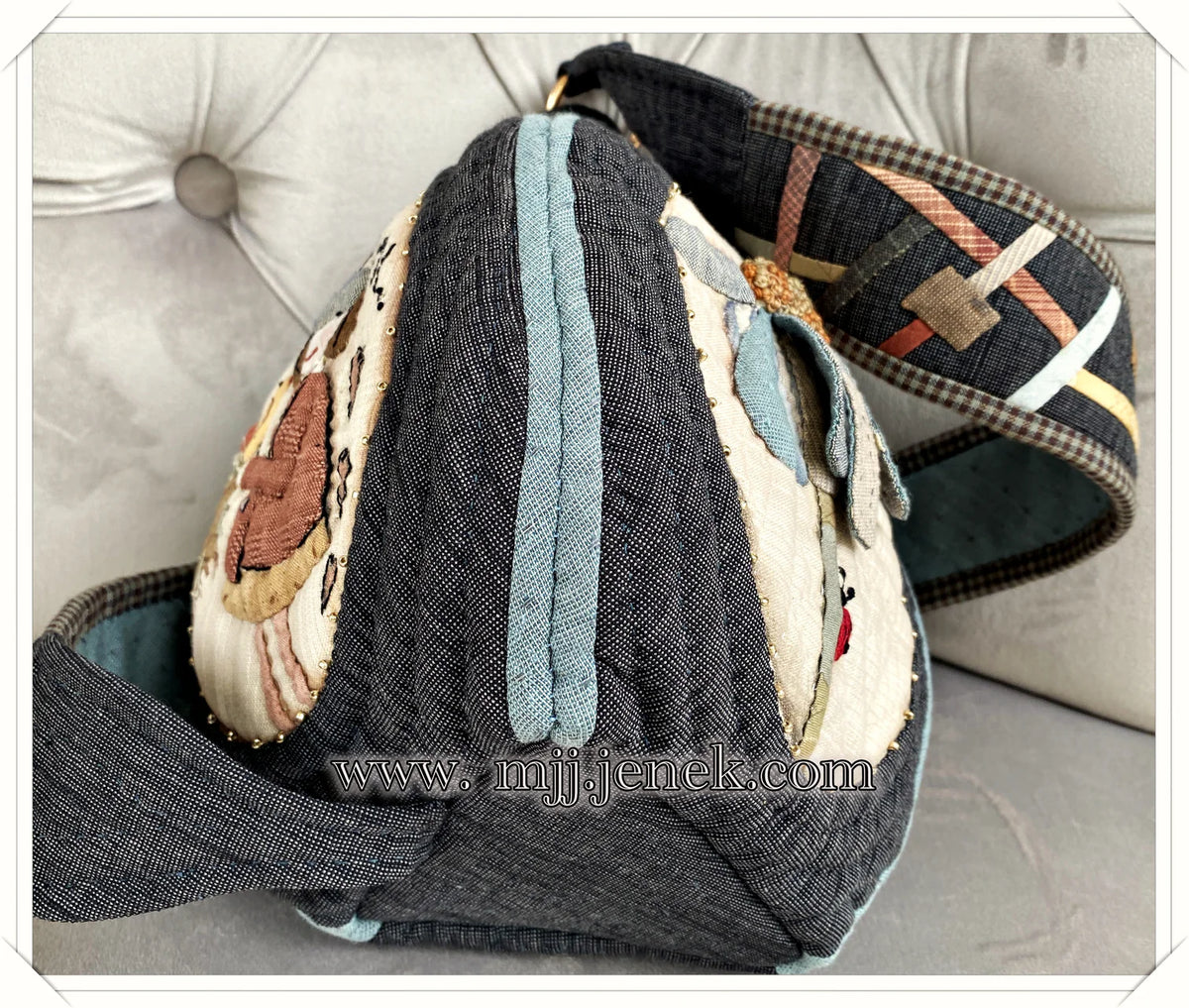 Handmade denim bag with colorful embroidery, unique shape, and adjustable strap.
