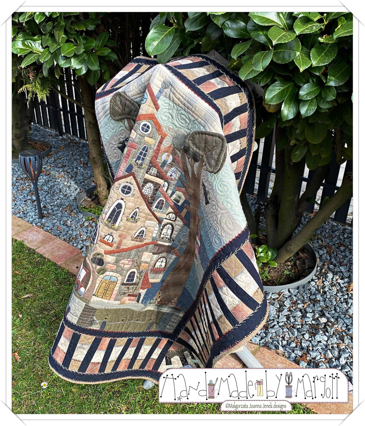 Colorful quilt featuring a whimsical house design, made of fabric with intricate quilting details.