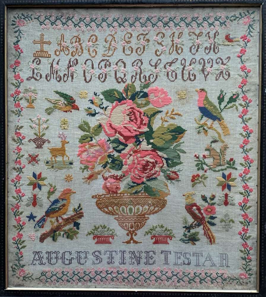 Vintage embroidered floral sampler featuring roses, birds, and decorative elements, framed art.