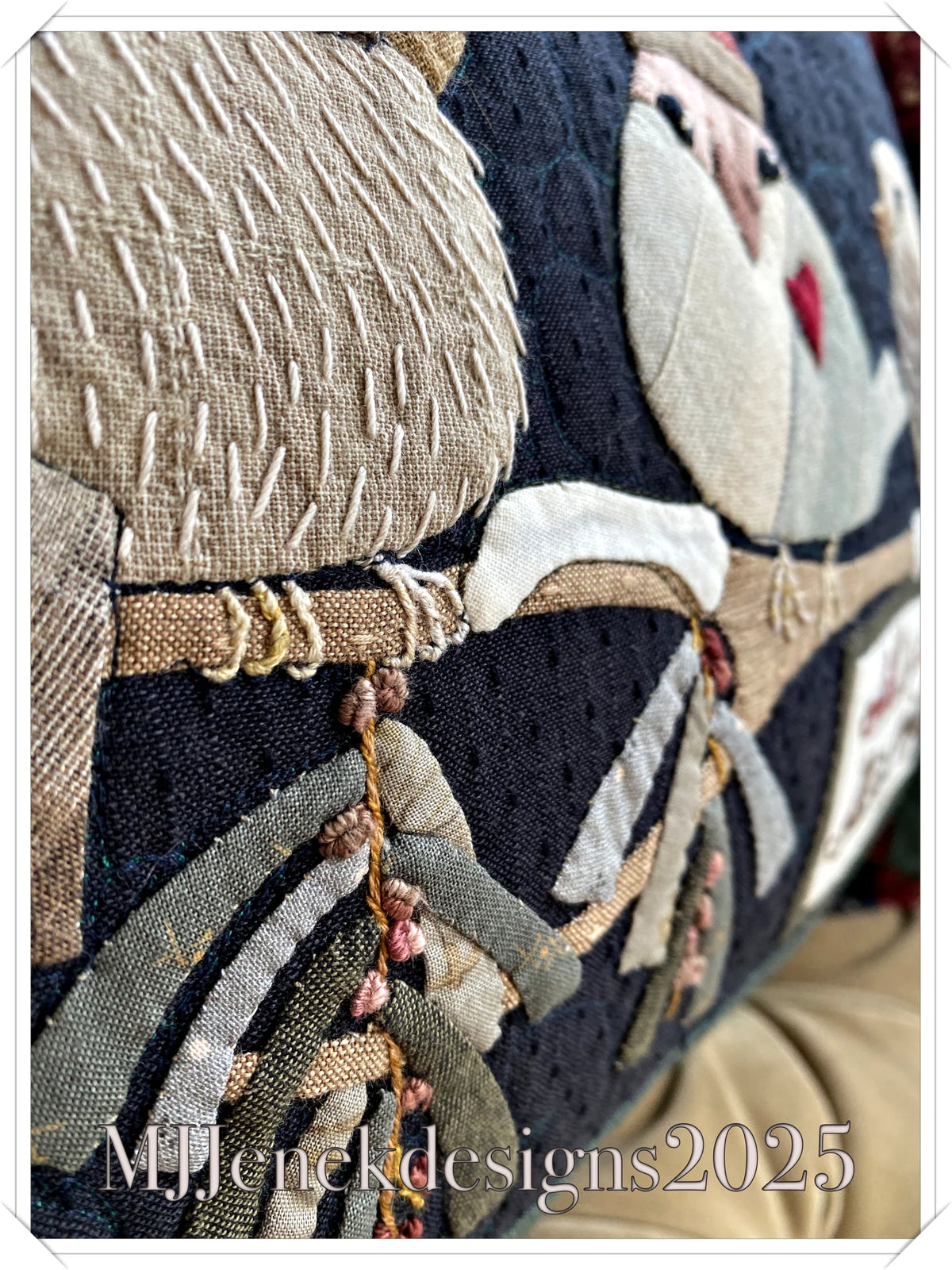 Close-up of embroidered fabric featuring a winter theme with animals, in neutral colors and a dark background.