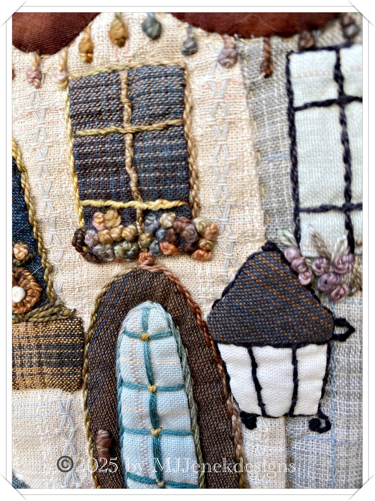 Hand-stitched fabric art featuring colorful houses with intricate detailing on linen and textured fabrics.