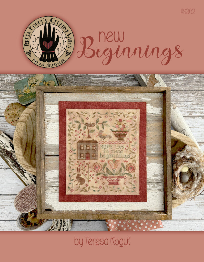 Framed cross-stitch design 'New Beginnings' by Teresa Kogut, featuring floral patterns on beige fabric.