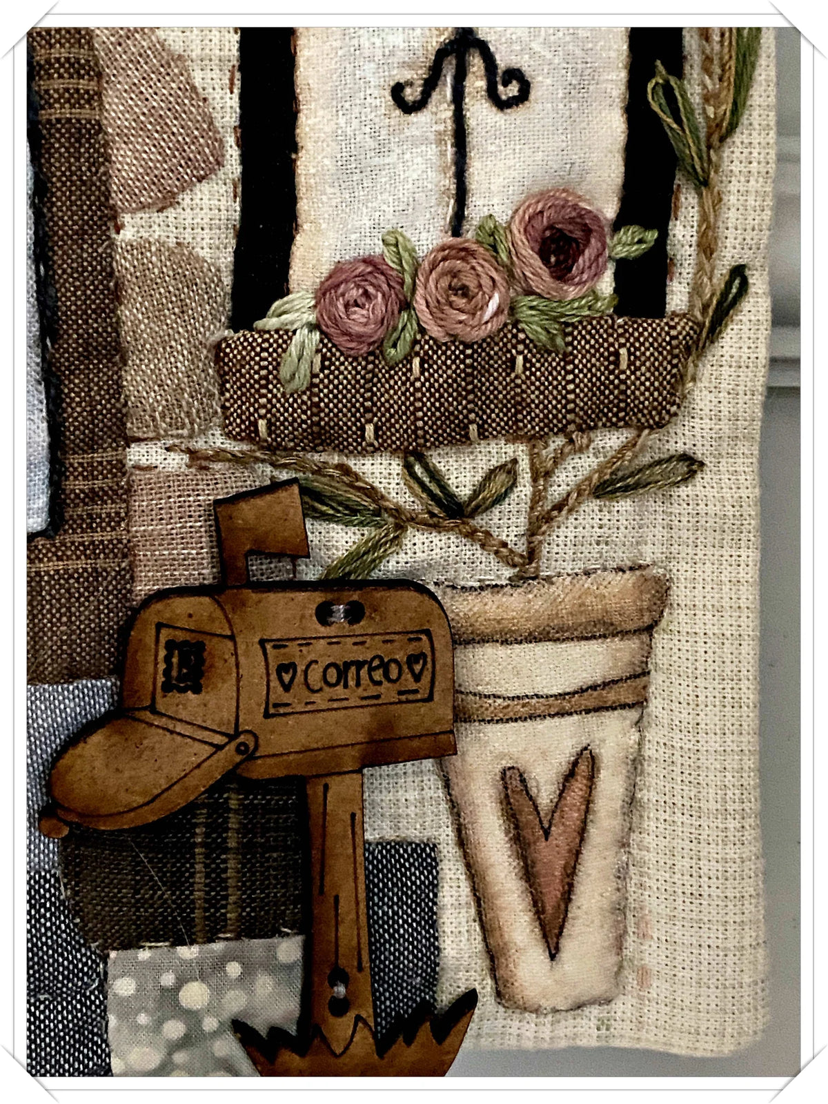 Decorative textile art featuring a mailbox, flowers, and earthy tones, perfect for home decor.