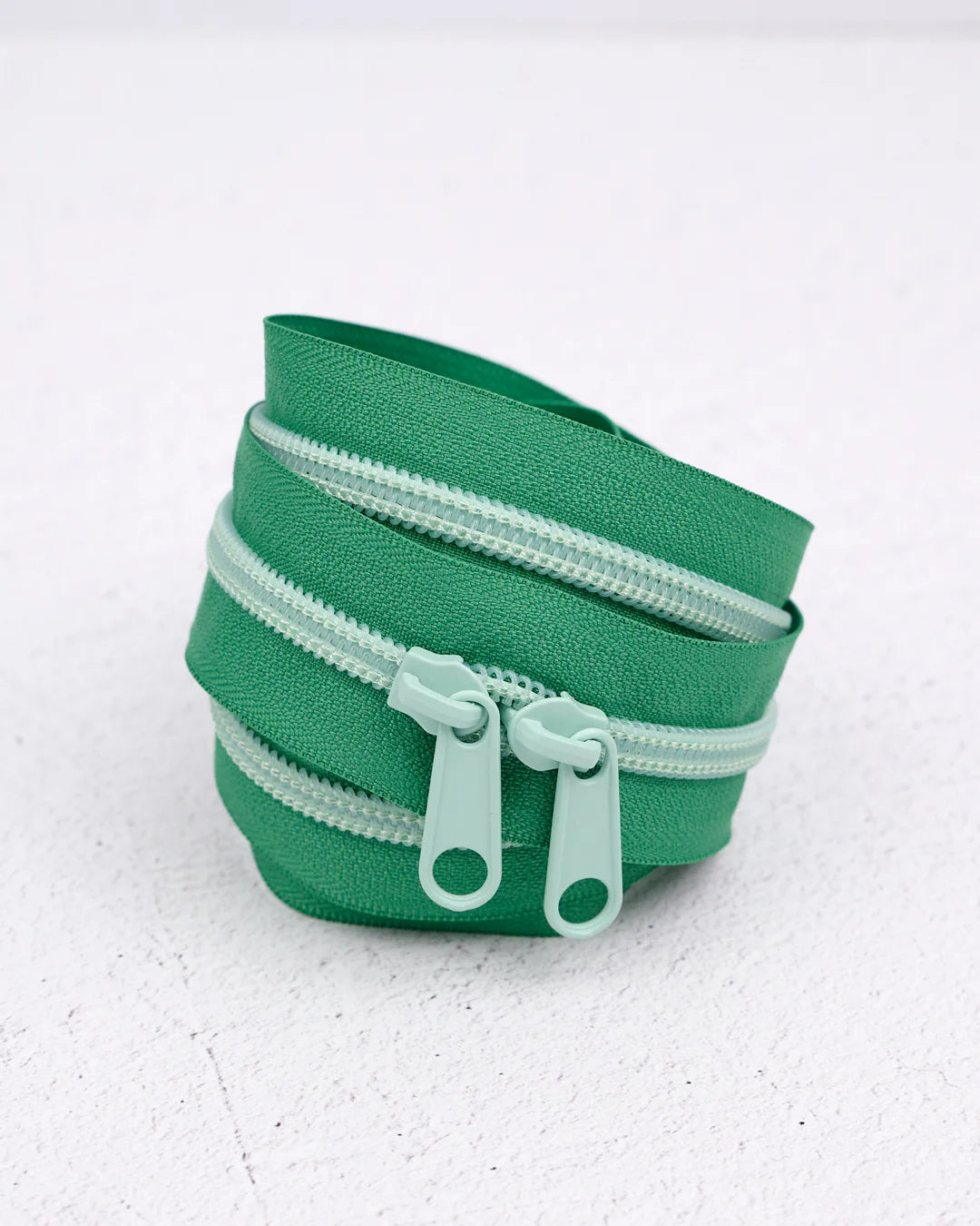 Green fabric storage pouch with dual zippers for organization and easy access.