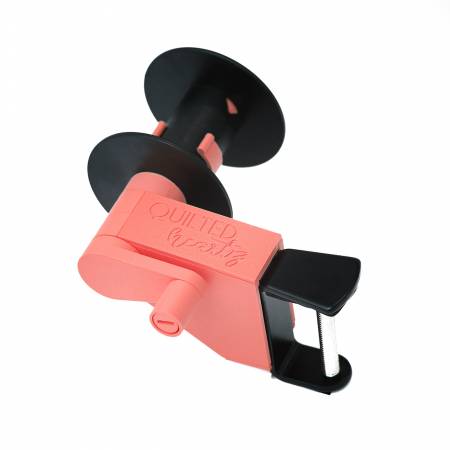 Coral quilting tool with a black clamp, designed for precise fabric alignment and easy handling.