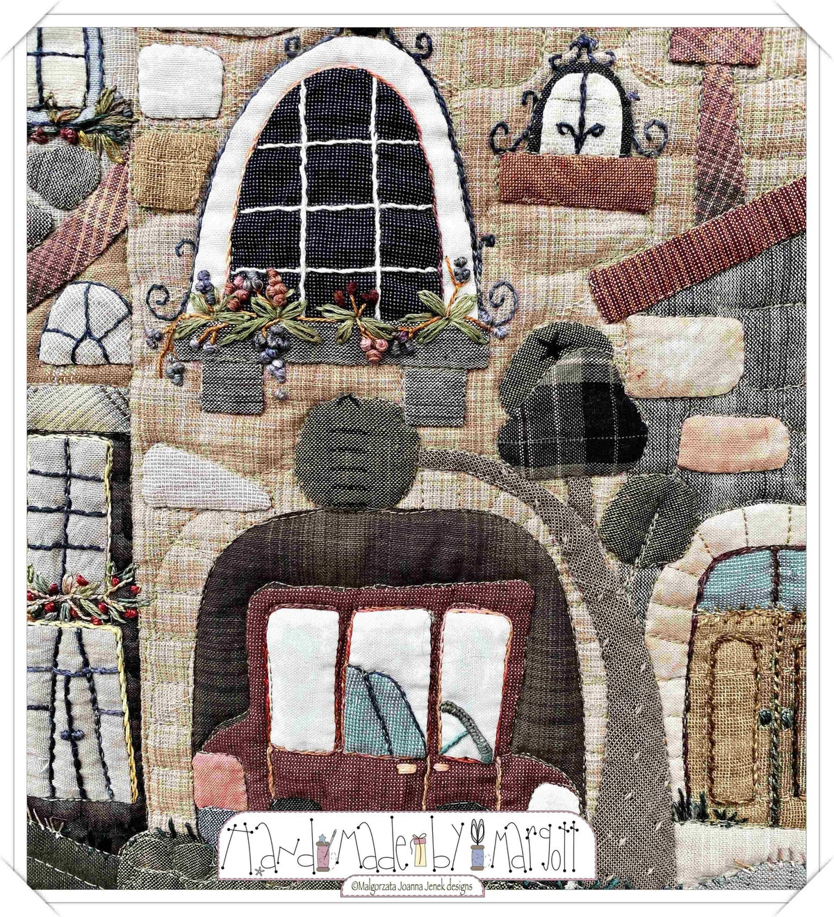 Quilted fabric art featuring a charming house with embroidered details, warm colors, and a vintage car.