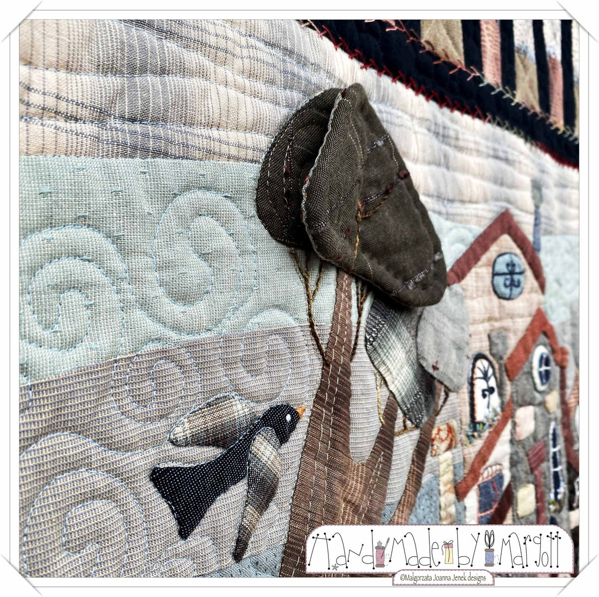 Handmade quilt detail featuring a bird, tree, and fabric textures in soft, muted colors.
