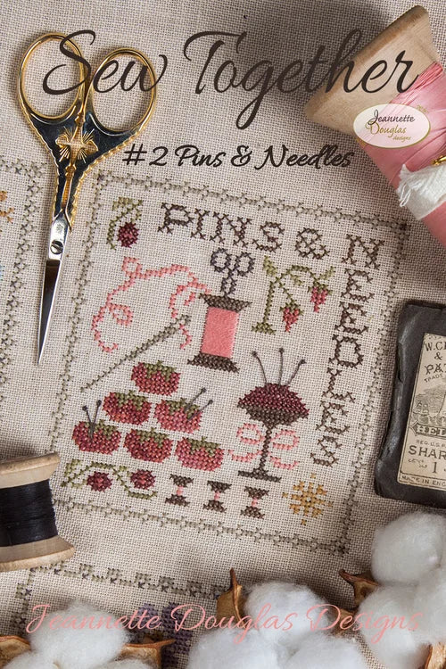 Cross-stitch kit featuring pins, needles, and sewing motifs on beige fabric with vibrant colors.