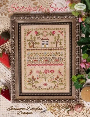 Framed cross-stitch pattern 'Stitches be Sweet' by Jeannette Douglas, featuring floral motifs and house design.
