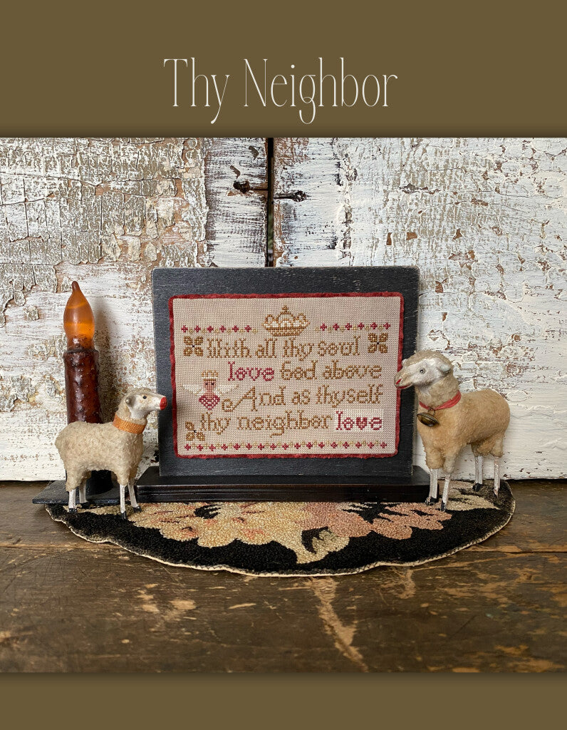 Framed 'Thy Neighbor' cross-stitch artwork with rustic sheep decor on a floral rug.