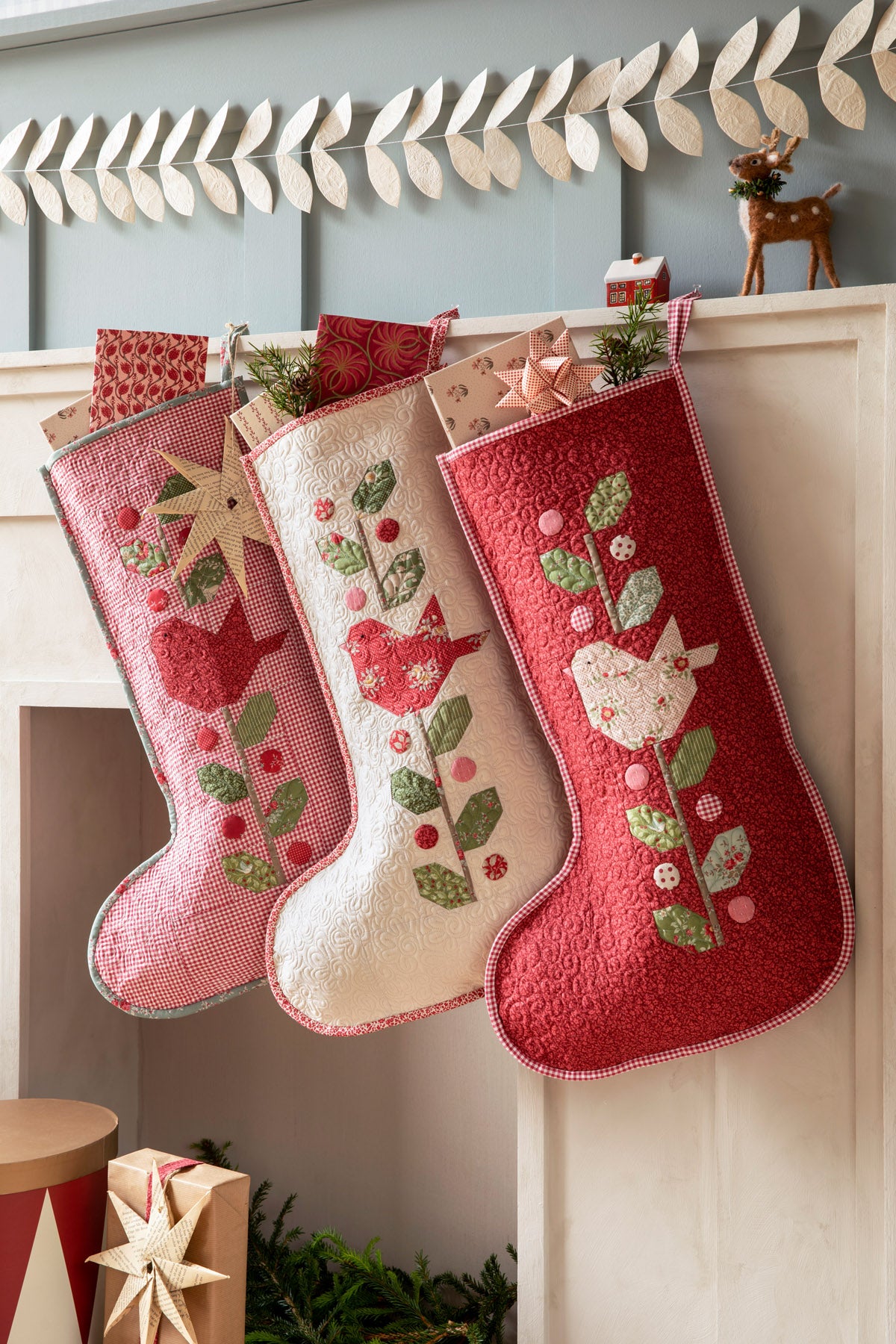Quilted Christmas stockings in red and cream, featuring embroidered birds and floral designs, perfect holiday decor.