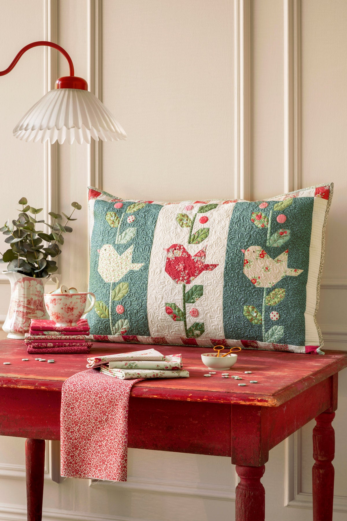 Colorful quilted pillow with birds, floral design, green and red, perfect for home decor.