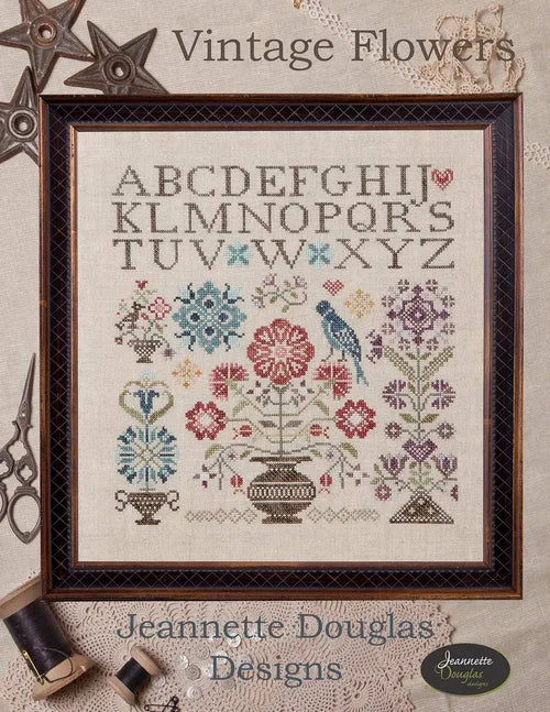 Framed vintage cross-stitch design featuring colorful flowers and birds, by Jeannette Douglas Designs.