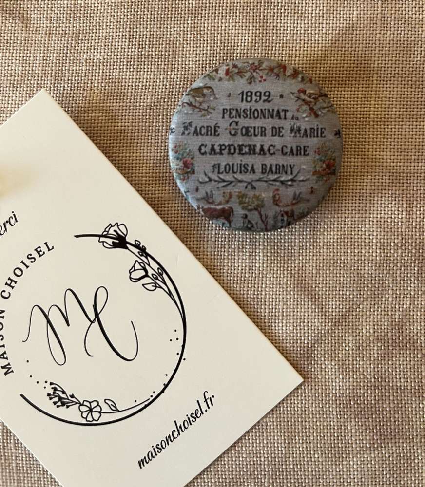 Antique round button from 1892 with floral design and text details, vintage collectible item.