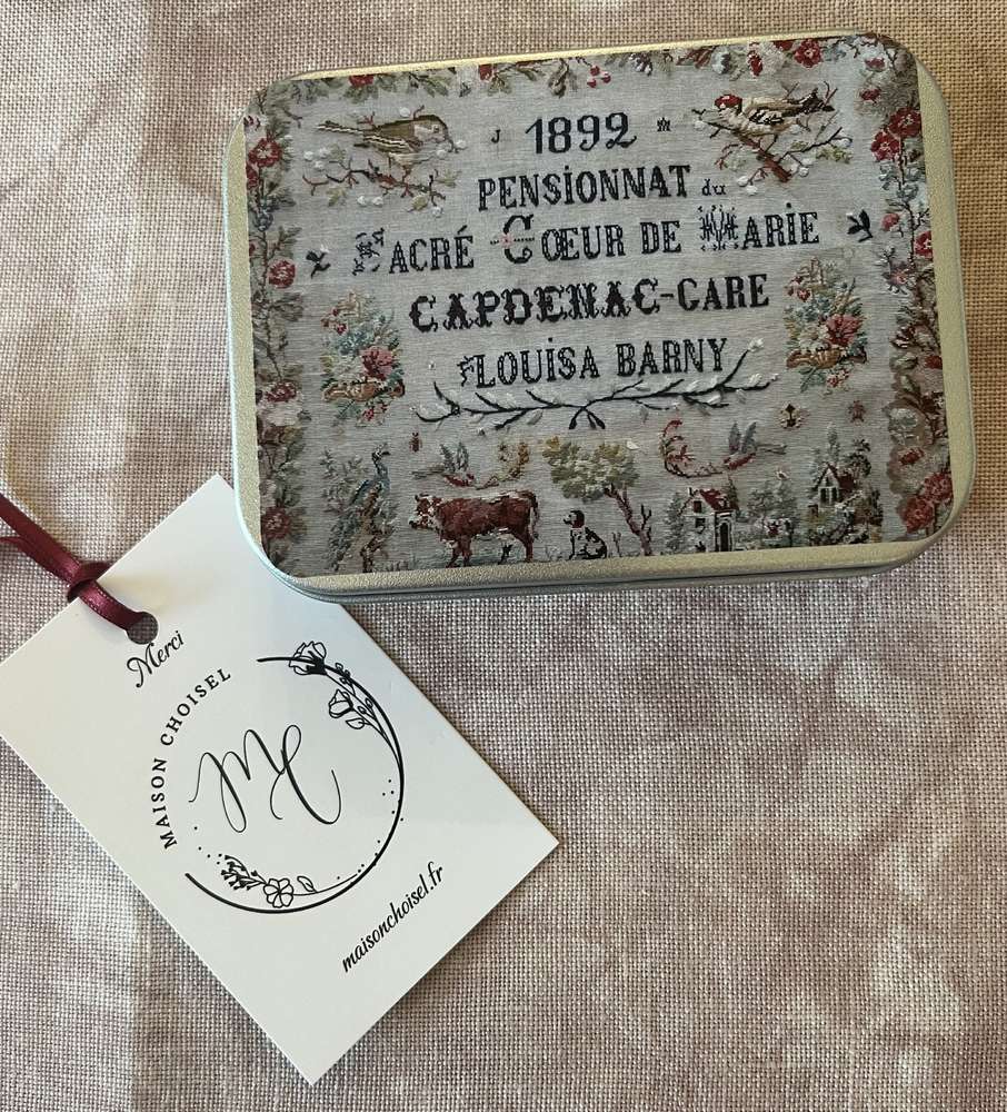 Vintage metal tin with embroidered floral design, featuring historical text and decorative tag.