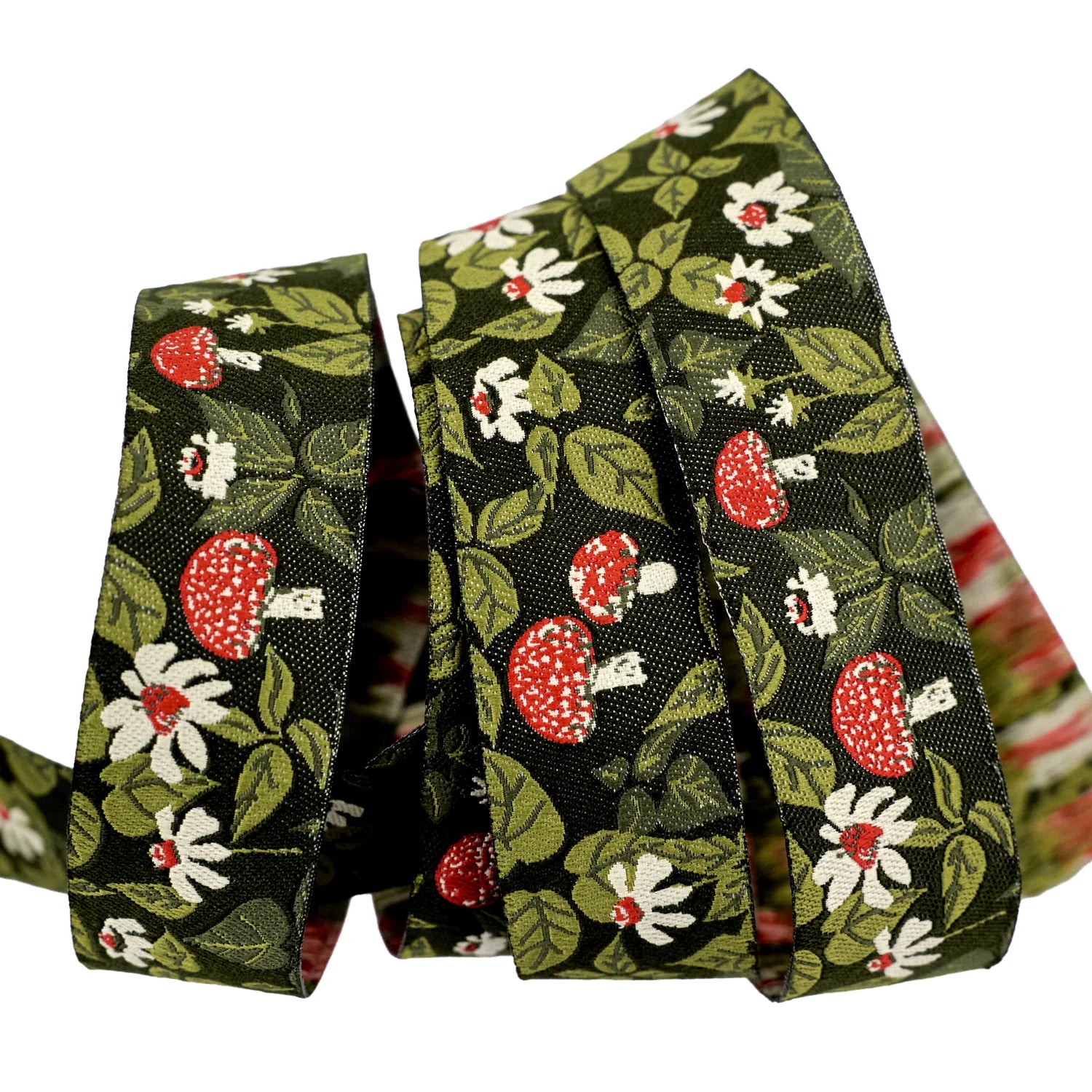 Floral patterned cotton ribbon in dark green with red mushrooms and white flowers, ideal for crafts.