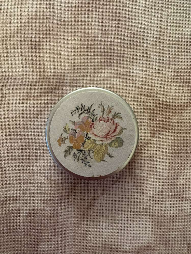Vintage floral round tin box with delicate rose design, perfect for storage or decor.