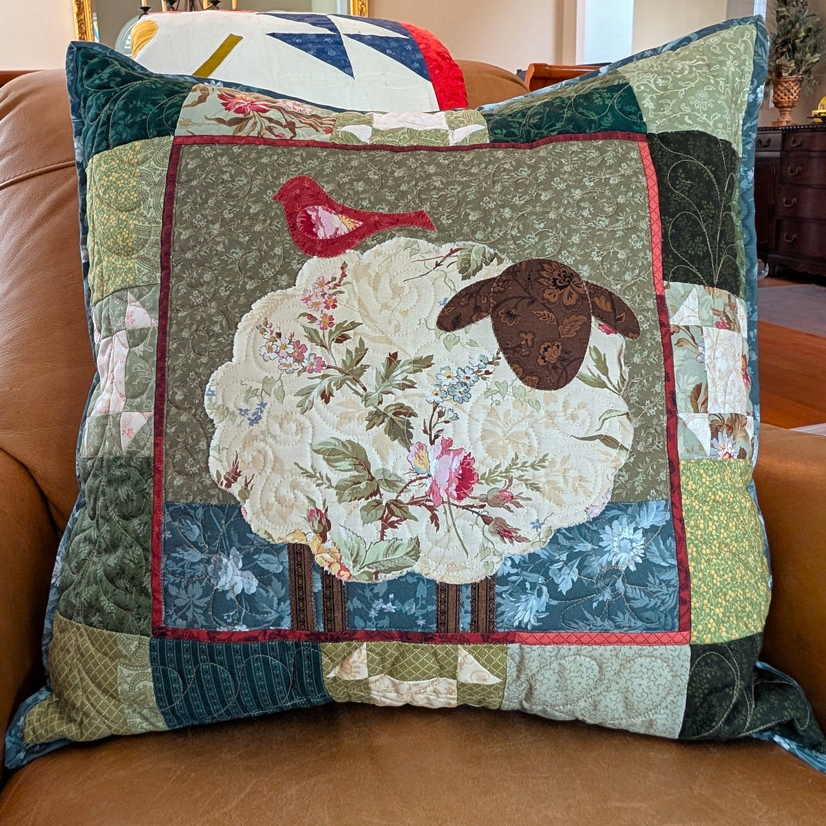 Colorful quilted decorative pillow featuring sheep and bird designs, made from assorted textiles.
