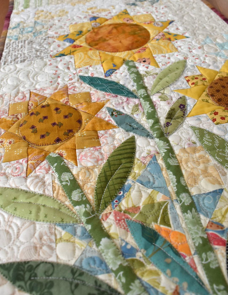 Quilted cotton table runner featuring bright sunflowers and green leaves in a patchwork design.