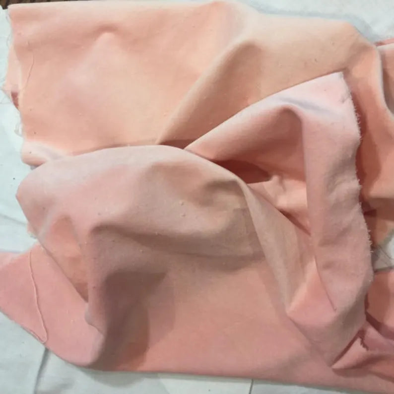 Soft pink cotton fabric draped elegantly, perfect for crafting or sewing projects.