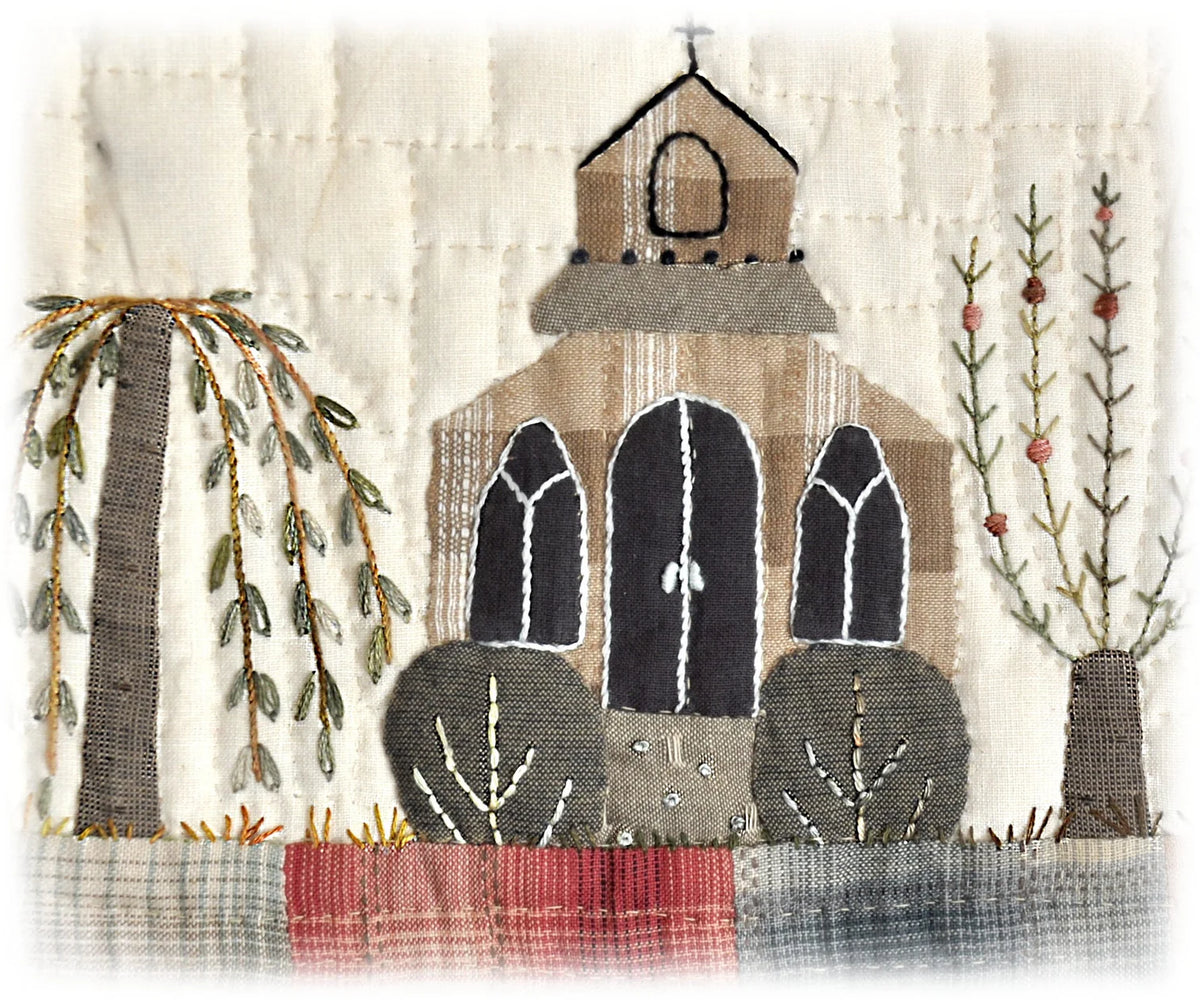Handcrafted fabric art featuring a church, trees, and colorful stitched details, ideal for home decor.