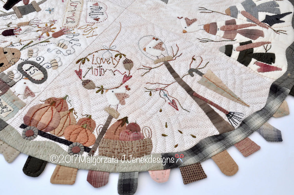 Autumn-themed quilt featuring pumpkins, birds, and decorative stitching, in warm pastel colors.