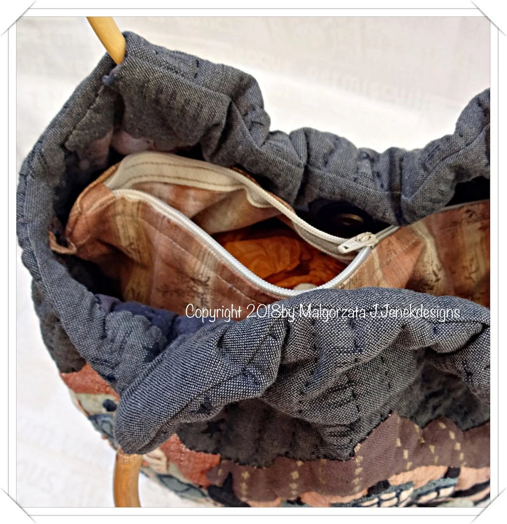 Handmade quilted tote bag in blue and earthy tones with a zippered interior pocket.