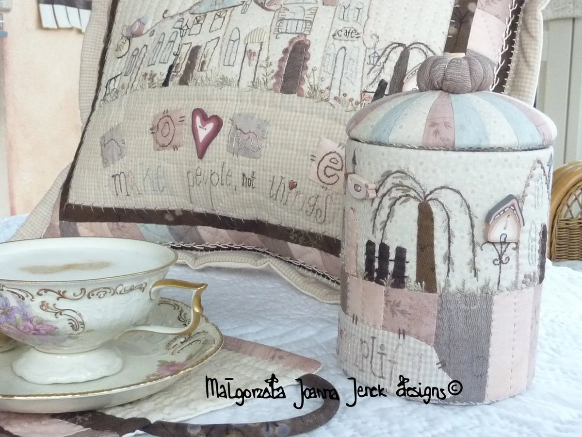 Decorative fabric container with pastel colors, featuring stitched patterns and a matching pillow.
