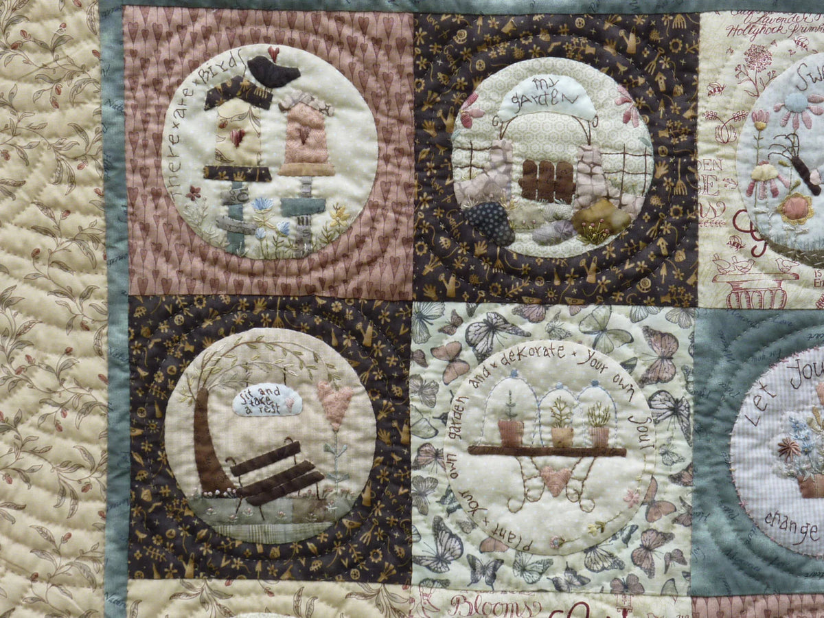 Patchwork quilt featuring floral designs and garden motifs in earthy colors and various fabrics.