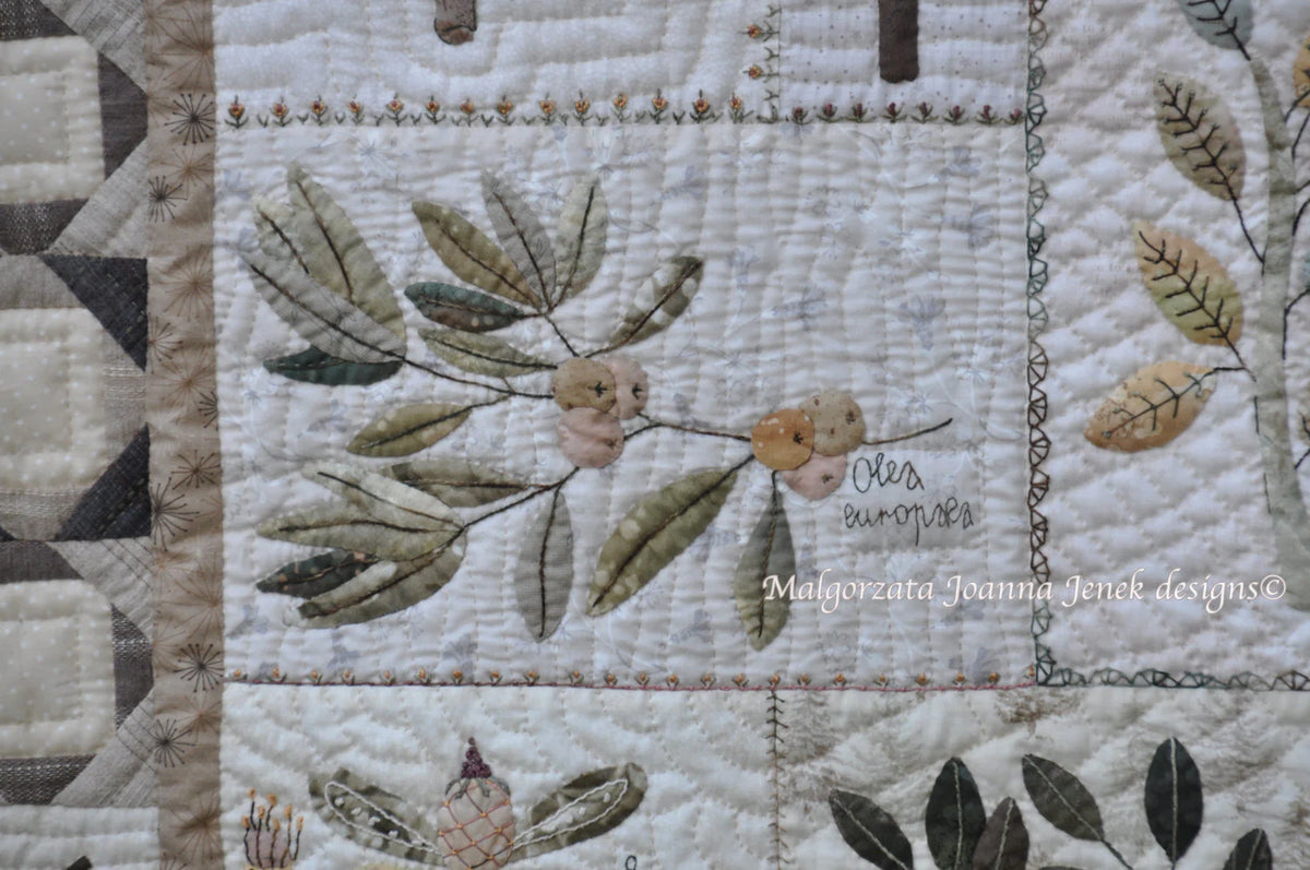 Handmade quilt with olive branches and leaves, featuring earthy tones and intricate stitching details.