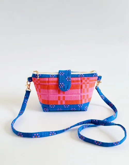 Colorful handmade crossbody bag in pink and blue with zip closure and adjustable strap.
