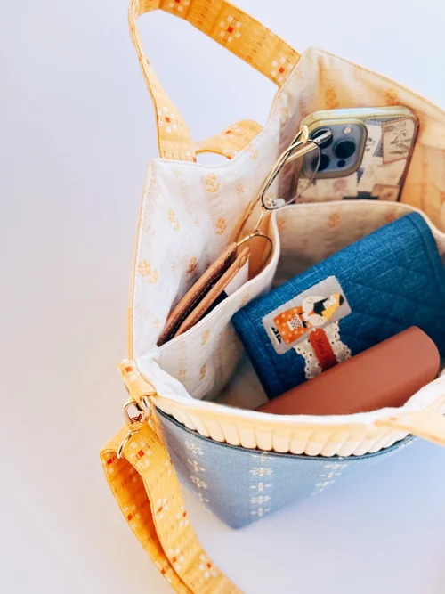 Stylish quilted blue tote bag with yellow straps, lined with a floral pattern, featuring multiple pockets.