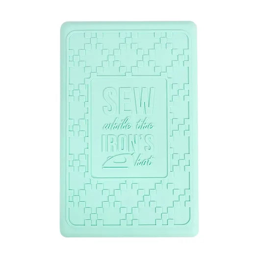 Mint green silicone pressing mat with embossed sewing and iron design for craft projects.