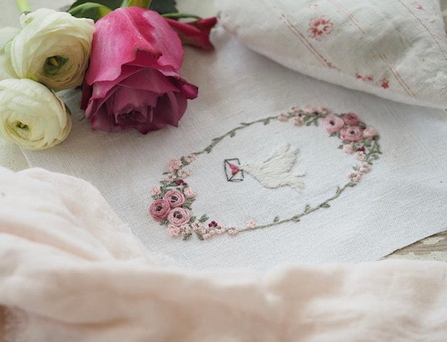 Embroidered linen cloth featuring a dove and pink flowers, perfect for home decor or gifts.